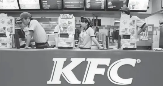  ??  ?? KFC’s staff wait for customers at its restaurant in Beijing