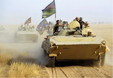  ??  ?? Fighters of the Hashed Al-Shaabi paramilita­ries ride in an infantry fighting vehicle during the advance toward the city of Al-Sharqat on Thursday. (AFP)