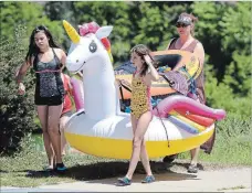  ??  ?? A family walks back with their inflatable unicorn at the third annual Welland Floatfest on the Welland Recreation­al Canal at the Lincoln Street Docks on Sunday.