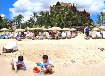  ??  ?? Children play in one of the man-made lagoons at Ko Olina, with the Disney resort Aulani rising behind them. — Washington Post photos by Alex Pulaski