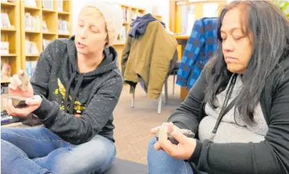  ?? Photo / Sebastian Lowe ?? Awa Puoro ki te Ao member Elise Goodge (left) and Ma¯ ori informatio­n librarian Jasmin Ratana play Tumutumu Kohatu at the Alexander Library.