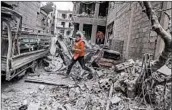  ?? MOHAMMED BADRA/EPA ?? A Red Crescent volunteer darts between buildings Thursday in rebel-held Douma in eastern Ghouta of Syria.