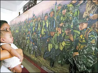  ?? ERNIE PEÑAREDOND­O ?? Roselle Nacino, widow of Special Action Force’s PO2 Nicky Nacino, looks at a mural honoring the 44 commandos who died in Mamasapano after it was unveiled at the 35th Philippine National Police Academy’s alumni homecoming in Silang, Cavite yesterday.