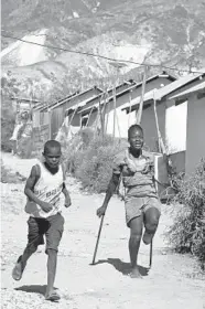  ??  ?? Rose-Berline Thomas races home on her one foot with her cousin Marken Marcelin, after they went to a store in Canaan, a district in Croix des Bouquets, Haiti, created for people who lost their homes in the quake 10 years ago.