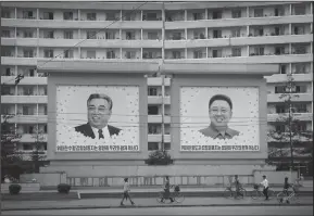  ?? Associated Press ?? North Korea: North Koreans are dwarfed against giant portraits of the late North Korean leaders Kim Il Sung and Kim Jong Il as they walk past an apartment building in Wonsan, North Korea. South Korea's Joint Chiefs of Staff said in a statement that...