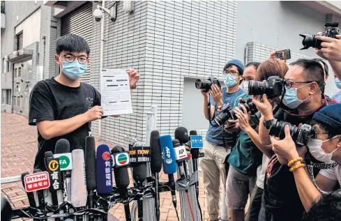  ?? AFP ?? Pro-democracy activist Joshua Wong speaks to the media while holding up a bail document after leaving Central police station in Hong Kong on Thursday.