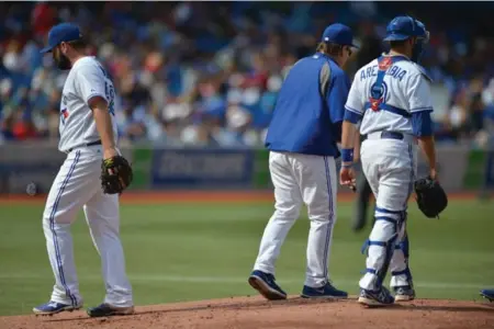  ?? CARLOS OSORIO/TORONTO STAR ?? Jays manager John Gibbons, centre, and catcher J.P. Arencibia await a new pitcher as starter Todd Redmond gets the hook in the first inning Sunday.