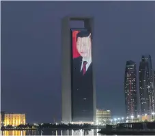  ?? Pawan Singh, Antonie Robertson / The National ?? Tourists, left, taking photos of the Dubai Frame lit up in red and an LED display on the Adnoc building in Abu Dhabi, right, to celebrate the visit