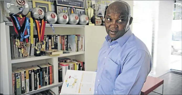  ?? PHOTOS: THULANI MBELE ?? Pitso Mosimane shows off one of his books in his Houghton, Johannesbu­rg home. The Sundowns coach is an avid reader, although his study is also filled up with his many accolades he’s won over the years, including a record five successive coach of the...