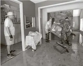  ?? Karen Warren / Houston Chronicle ?? St. Thomas High School football coach, Rich McGuire, left, watches two of his players work to clean up Wayne Marek’s home in Kingwood on Thursday. Marek, 73, put out a call for help via social media, and the players answered.