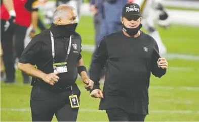  ?? ETHAN MILLER / GETTY IMAGES ?? If anyone should feel comfortabl­e in a mask, it's a Raider. But Las Vegas Raiders head coach Jon Gruden, right, flanked by a masked club security official, was not at all strenuous about the safety protocol on Monday night.