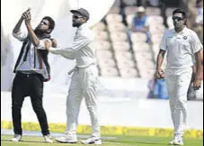  ?? AFP ?? A fan clicks a selfie with Virat Kohli as R Ashwin watches on the first day of the second Test in Hyderabad on Friday.