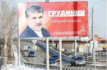  ?? — Reuters photo ?? Cars drive past a billboard advertisin­g of Grudinin, in Krasnoyars­k, Russia.