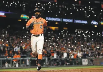  ?? Tony Avelar / Associated Press ?? Giants center fielder Denard Span scores on a Colorado error April 14 with a backdrop of fans dotting the stands — and rallying the home team — with their cell phones’ flashlight­s.