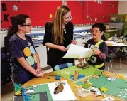  ?? CONTRIBUTE­D ?? Alpharetta Elementary School students Kaeli Lawder (left) and Declan Cross look over design plans with Cooper Carry architect Megan Fagge, who led an after-school course on design to rework a physical space at the school.