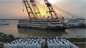  ?? THE ASSOCIATED PRESS ?? Policemen in white overalls wait to recover bodies from the Eastern Star in Jianli, China on Friday.