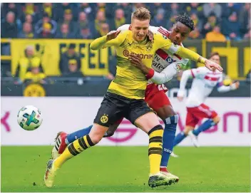  ?? FOTO: KIRCHNER/DPA ?? Marco Reus ist wieder zurück im Team von Borussia Dortmund. Hier lässt er sich auch von der Umklammeru­ng des Hamburgers Gideon Jung nicht vom Ball trennen. Reus bot am Samstag zum Einstand ein gutes Spiel.
