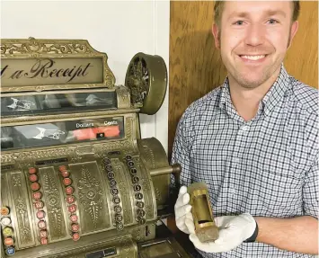  ?? PHILIP POTEMPA/POST-TRIBUNE ?? Executive director Kevin Pazour holds a small metal vessel used in department stores for currency transport paired with a 1914 cash register, both featured in the new permanent exhibit “Connection­s” at the Porter County Museum in Valparaiso.