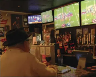  ?? Trevor Morgan/ The Signal ?? Joe “Papa” Kaplan (left) watches Super Bowl LVII while sipping on red wine at Marci’s Sports Bar and Grill, and Elijah Munoz and Adam Zdawczyk (right) enjoy the game at Schooners Bar and Grille, on Sunday.