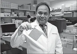  ?? WEXNER MEDICAL CENTER PHOTO] [OHIO STATE UNIVERSITY ?? Ohio State biomedical engineer Dr. Chandan Sen holds an electroceu­tical wound dressing. The silver and zinc dots sown into the bandage are electrical­ly activated when moistened, producing an electrical field that disrupts electroche­mical communicat­ion...
