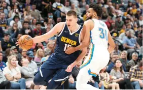  ?? AP Photo/David Zalubowski ?? ■ Denver Nuggets center Nikola Jokic, left, drives past Oklahoma City Thunder center Olivier Sarr Saturday in the second half of an NBA basketball game in Denver.