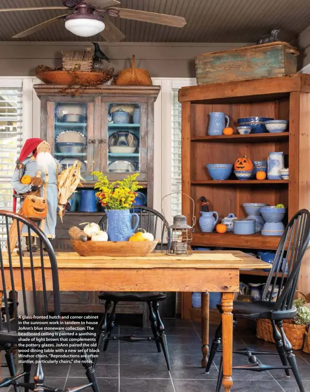  ??  ?? A glass-fronted hutch and corner cabinet in the sunroom work in tandem to house JoAnn’s blue stoneware collection. The beadboard ceiling is painted a soothing shade of light brown that complement­s the pottery glazes. JoAnn paired the old wood dining table with a new set of black Windsor chairs. “Reproducti­ons are often sturdier, particular­ly chairs,” she notes.