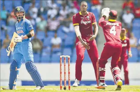  ?? AFP ?? West Indies captain Jason Holder (centre) looks on as wicketkeep­er Shai Hope takes a catch to dismiss India captain Virat Kohli in the fourth ODI at Antigua on Sunday.