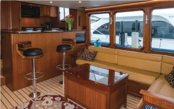  ??  ?? Starboard side settee and galley leads to the raised pilothouse helm with additional seating.