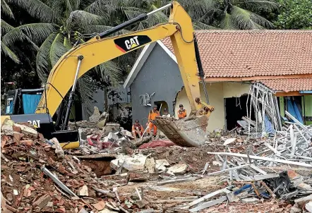  ?? AP ?? An excavator is used to clean up the debris following a tsunami in Carita beach, Indonesia.