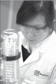  ?? PROVIDED TO CHINA DAILY ?? (left) discuss use of equipment at the central chemistry lab of BeiGene in Beijing in May 2017. A BeiGene scientist (right) examines a sample during a test.