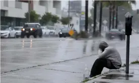  ??  ?? A homeless man sits on a curb in the pouring rain in the Mar Vista neighborho­od of Los Angeles. Photograph: Genaro Molina/Los Angeles Times/REX/Shuttersto­ck