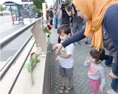  ?? — AFP ?? A woman and her children light candles to commemorat­e victims at the entrance of the subway station near the shopping mall in Munich on Saturday.