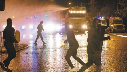  ?? PAUL FAITH AFP VIA GETTY IMAGES ?? Police officers use a water cannon as they clash with nationalis­t youths in Belfast on Thursday as disorder continued in the Northern Ireland capital following days of mainly loyalist violence. Northern Ireland police faced a barrage of gasoline bombs and rocks Thursday.