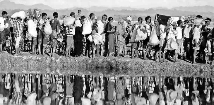  ??  ?? Rohingya refugees who fled from Myanmar wait to be let through by Bangladesh­i border guards after crossing the border in Palang Khali in October 2017.