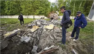  ?? ANDRII MARIENKO / ASSOCIATED PRESS ?? People look at fragments of the television tower that was broken in half after it was hit by a Russian missile in Kharkiv, Ukraine, on Monday.