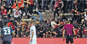  ??  ?? Chaos: Fans tumble on top of each other after a barrier collapsed in Amiens (above); Lille supporters and players celebrate Fode Ballo-Toure’s goal seconds before the collapse of the barrier (right)