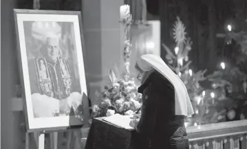  ?? ANDREAS SCHAAD AP ?? A woman signs a condolence book for Pope Emeritus Benedict XVI at the Saint Magdalena church in Altoetting, Germany, on Saturday, hours after the German theologian, who will be remembered as the first pope in 600 years to resign, died.