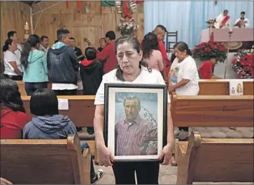  ?? Photograph­s by Gary Coronado Los Angeles Times ?? GEORGINA QUIROZ PEÑALOZA carries a photo of her father, Albino Quiroz Sandoval, after a Mass at Parroquia Nuestra Señora de la Natividad on Dec. 15 in Tepoztlán in Mexico’s Morelos state.