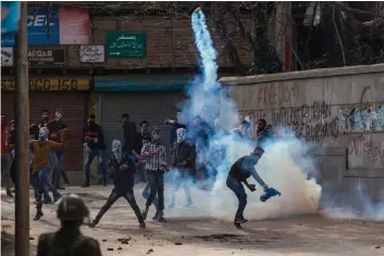  ??  ?? Masked protesters throw rocks at policemen in Srinagar, Kashmir AP —