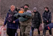  ?? AFP ?? In fuga Civili ucraini accompagna­ti da un militare polacco al confine tra i due Paesi: sarebbero almeno 1,3 milioni i profughi entrati nel Paese
