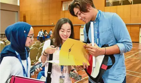  ??  ?? Asyiela (middle) with Adam Muqrish (right) are discussing the registrati­on process while another student Nuhasakina­h Saiful Bahrin looks on at the Cyberjaya campus.