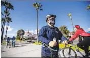  ?? Allen J. Schaben Los Angeles Times ?? BICYCLISTS not wearing face coverings ride past Long Beach “health ambassador” Chris Bonomo.