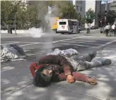  ??  ?? Homeless people sleep on the ground next to the Asian Art Museum near Civic Center. The area is a study in contrasts, with tents set up for voting and nearby restaurant­s serving diners.