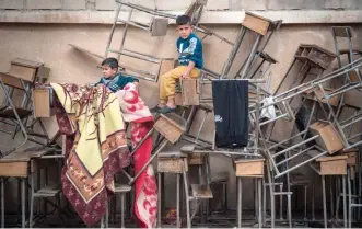  ?? — AFP ?? Displaced Syrian children sit on classroom tables at a school turned into a shelter for people displaced by the war in the northeaste­rn Syrian town of Hasakeh.