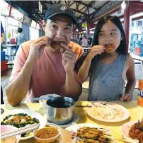 ?? (Tessa Pierson/Los Angeles Times/TNS) ?? THE REPORTER David Pierson eating fried chicken wings with his daughter, Ella, at Toa Payoh Lorong Food Center.