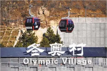  ?? MARK SCHIEFELBE­IN AP ?? Gondolas glide past a sign for the Olympic Village, where pandemic bubble restrictio­ns were in place.