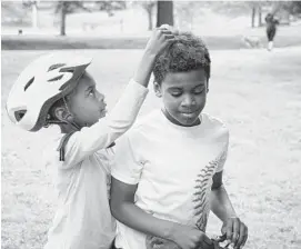  ?? ULYSSES MUÑOZ/BALTIMORE SUN ?? Lydia Wesby, 7, adjusts her 9-year-old brother Mitchell’s hair after he took his helmet off in Patterson Park. We are asking more of our parks than ever before.