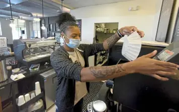  ?? Darrell Sapp/Post-Gazette ?? Kiya Heard pours coffee beans into the grinder at the Everyday Cafe in Homewood.