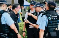  ?? Photo: May Tse ?? A man in a black shirt is questioned by police before being taken away after he was found with candle near Victoria Park.