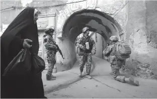  ?? Associated Press ?? ■ In this Thursday, April 23, 2009, file photo, an Iraqi woman passes U.S. troops and Iraqi police officers as they stand guard in the Bab al-Jadeed area of Mosul, 225 miles northwest of Baghdad.